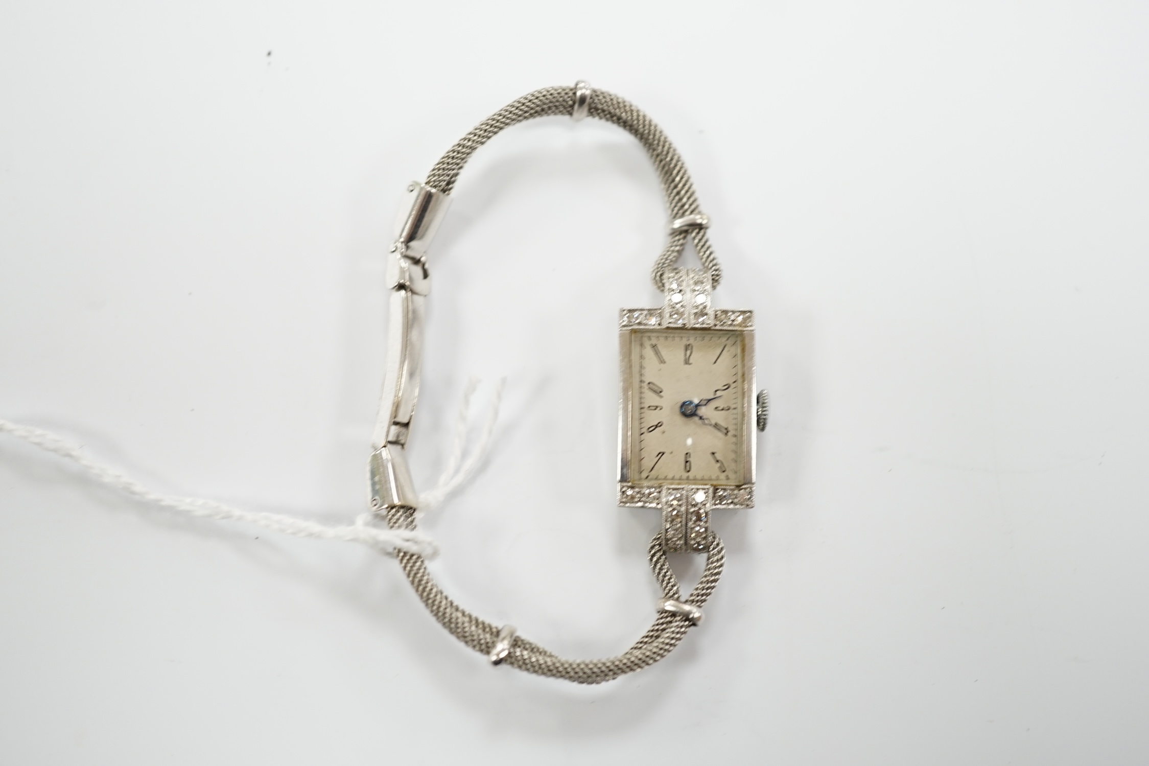 A lady's white metal and diamond set rectangular dial manual wind cocktail watch, on a 9ct white gold, bracelet, gross weight 17.4 grams.